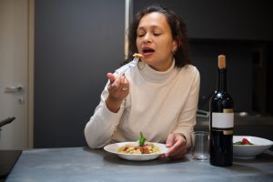 Woman,Eating,A,Delicious,Pasta,Meal,With,A,Glass,Of